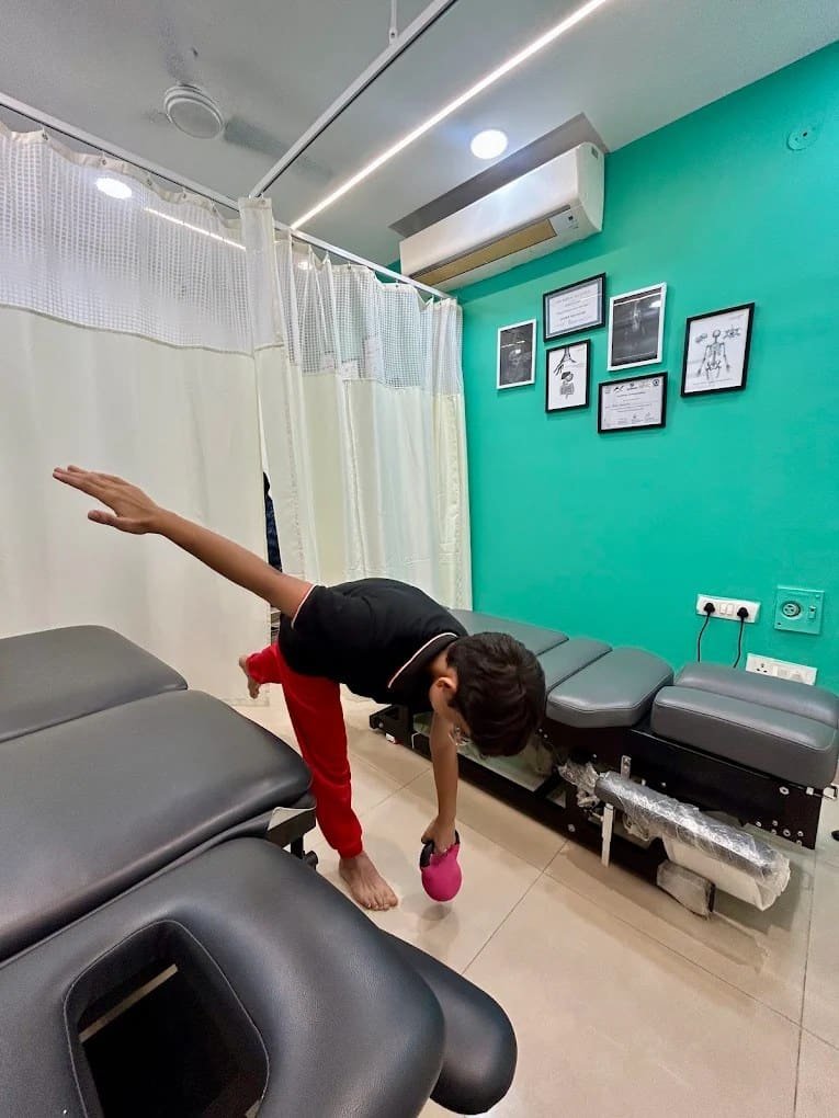 Patient performing a guided mobility stretch on a treatment table at Symphysio, Sarita Vihar